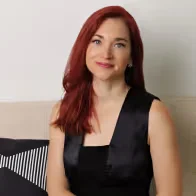 Una mujer con una larga melena roja, vestida con un elegante vestido negro, que irradiaba gracia y elegancia en su apariencia.