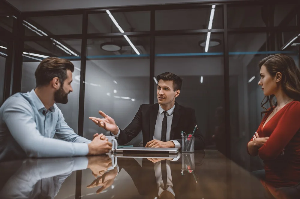 A mediation meeting: two men and a woman talking across a conference table